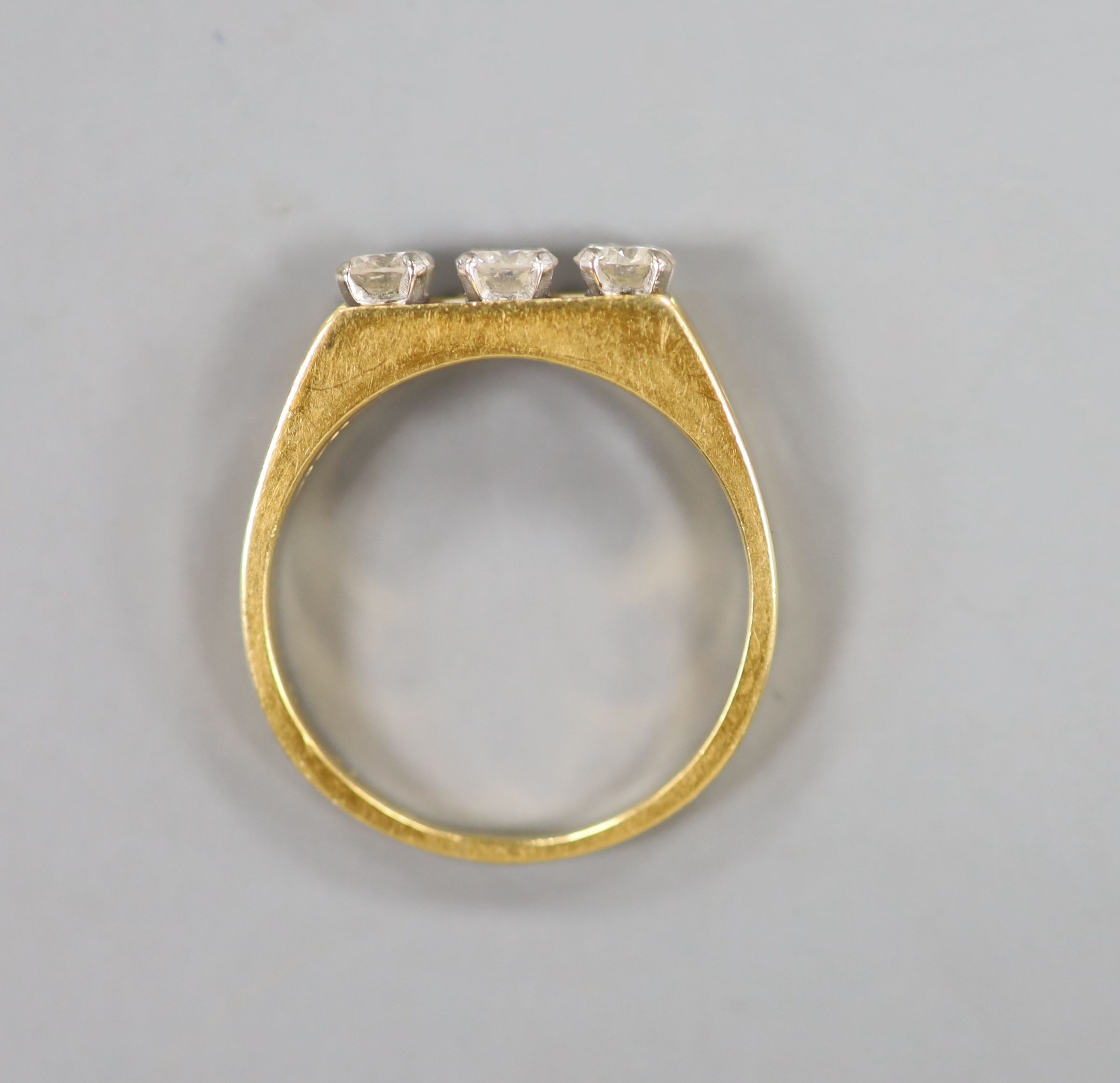 An 18ct and channel set three stone diamond ring, size P, gross weight 4.4 grams.